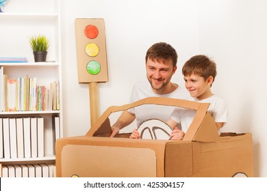 Happy Kid And His Dad Driving Toy Cardboard Car