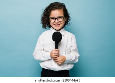 Happy kid holding a microphone and doing an interview while playing host or journalist career - Shutterstock ID 2198444695