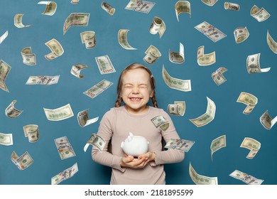 Happy Kid Laughing And Holding White Piggy Bank In American Dollar Money Rain On Blue Background