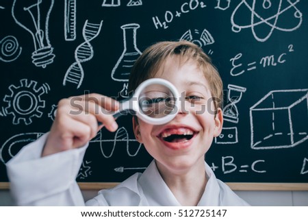 Happy kid looking at camera through magnifying glass