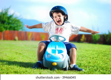 Happy Kid On Green Meadow Driving A Car