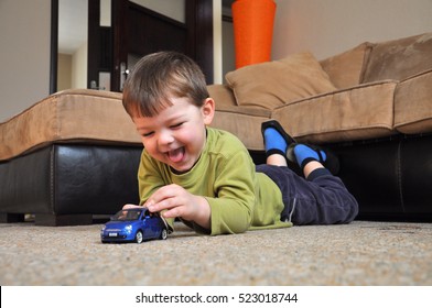 Fröhliches Kind spielt mit seinem Autospielzeug