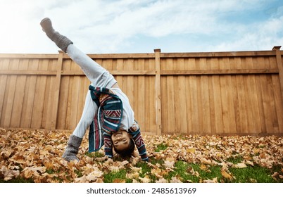 Happy kid, playing and cartwheels in outdoor, healthy and cheerful for growth, fun and development. Child, girl and activity in autumn for joy, energy and skills as preschooler in backyard or garden - Powered by Shutterstock