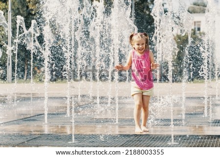 Happy kid playing in a fountain with water