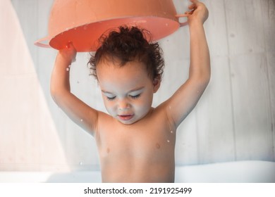 Happy Kid Playing In An Inflatable Pool In Backyard. Curly Toddler Smiling And Playing With Water