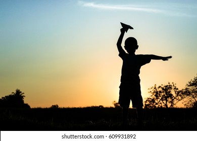 Happy Kid Playing With Paper Airplane In The Sunset