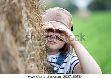 Similar – Junge Frau bedeckt ihr Gesicht vor der Sonne auf einem grünen Feld.