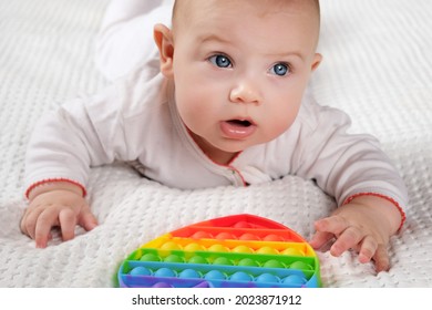 Happy Kid Playing with Pop It. Newborn Baby Playing with Simple Dimple. The Flexible Sensory Fidget Push-Bubble Toy is Good for Baby Development. Little Child Holds an Eternal Bubble in her Mouth.