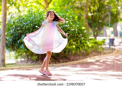 Happy Kid Playing In Summer Park. Little Girl Dancing In Beautiful Dress. Children Run, Spin, Twirl And Laugh. Summer Vacation Fun. School Holiday Activity. Easter Or Child Birthday Party.