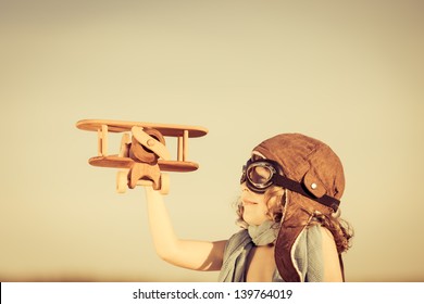 Happy Kid Playing With Toy Airplane Against Blue Summer Sky Background.