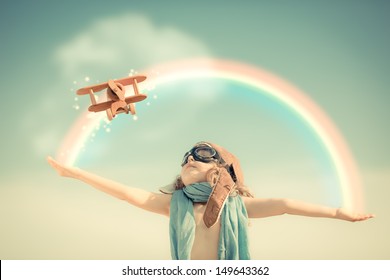 Happy Kid Playing With Toy Airplane Against Summer Sky Background