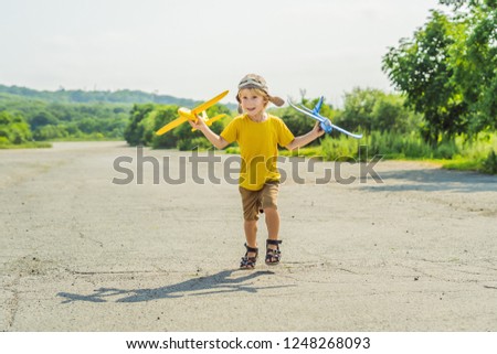 Happy kid playing with toy airplane against old runway background. Traveling with kids concept