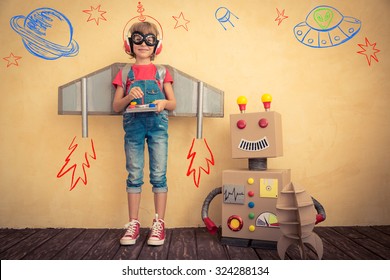 Happy kid playing with toy robot at home. Innovation technology and success concept - Shutterstock ID 324288134