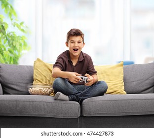 Happy Kid Playing Video Games And Sitting On A Sofa