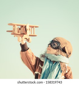 Happy Kid Playing With Wooden Toy Airplane In Autumn