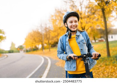 Happy kid riding scooter on autumn road to school. Teenager in protective helmet on cycleway. Girl smiling on town street. Safety childhood, healthy outdoor activities. Authentic lifestyle moment. - Powered by Shutterstock