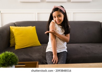 Happy Kid Smiling And Showing The Band Aid Of Her Arm After Getting Vaccinated