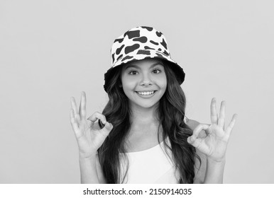 Happy Kid In Summer Bucket Hat Has Curly Hair On Yellow Background, Ok