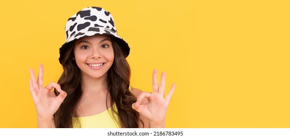 Happy Kid In Summer Bucket Hat Has Curly Hair On Yellow Background, Ok. Child Face, Horizontal Poster, Teenager Girl Isolated Portrait, Banner With Copy Space.