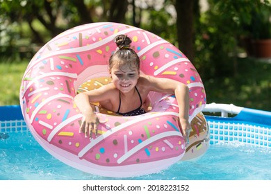 Happy kid swim in donut pool float in swimming pool on sunny summer day, floatation