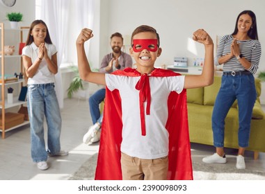 Happy kid wearing superhero costume. Smiling hero child showing muscles. Cheerful boy disguised as good movie and comic book character is ready to defend family, save world and go to fancy dress party - Powered by Shutterstock