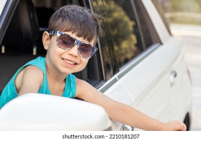 Happy Kid In White Car Looking In Rear View Retractable Lateral Mirror Through Lateral Door Window.joyful Child Boy Ready Fir Trip Travel By Car.family Adventure Smiling Kid Hands Up Expressing Hooray