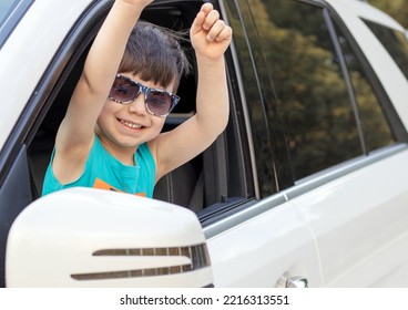 Happy Kid In White Car Looking In Rear View Retractable Lateral Mirror Through Lateral Door Window.joyful Child Boy Ready Fir Trip Travel By Car.family Adventure Smiling Kid Hands Up Expressing Hooray