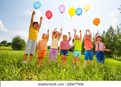 Happy Kids With Balloons And Arms Up In The Sky