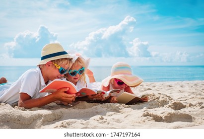 happy kids -boy and girls- read books on beach, summer reading on vacation