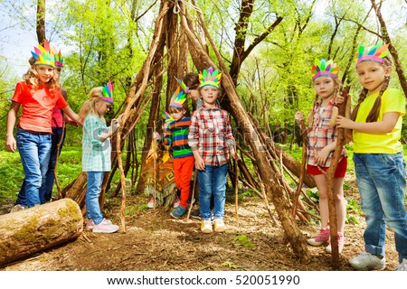 Happy kids building wigwam in the forest