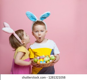 Happy Kids In Bunny Ears Whispering To Shocked And Surprised School Boy In Ear. Family Having Fun On Easter Egg Hunt. Kids Playing With Rabbit. Children With Easter Eggs In Basket. Whispering Secret