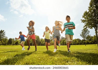 Happy kids, diversity and running with friends in nature for fun, playful day or summer at park. Group of excited children or youth enjoying sunny outdoor holiday or weekend on grass field together