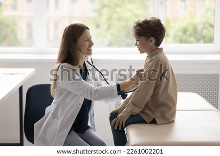 Happy kids doctor examining child for heart disease, flu, respiratory infection, applying stethoscope to boys chest, listening heartbeat rate, breathing, talking to little patient, smiling