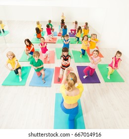 Happy Kids Doing Kneeling Exercises In Gym