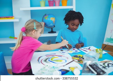 Happy Kids Enjoying Arts And Crafts Painting At Their Desk