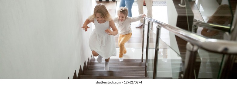 Happy kids go upstairs to second floor their new modern house, family moving day relocation and loan, buy first home concept. Horizontal photo banner for website header design with copy space for text - Shutterstock ID 1296270274