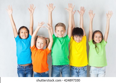Happy kids hands up, smiling and posing at white background.