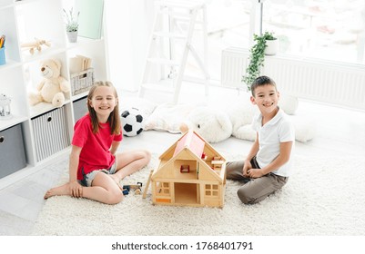 Happy Kids Having Fun With Wooden Dollhouse In Play Room, Top View