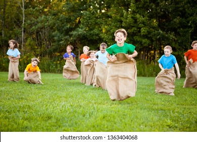 Happy Kids Having Potato Sack Race Outside