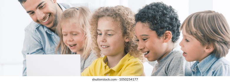 Happy Kids Looking At A Laptop Screen, Discovering The Fun Of Coding With Help Of Informatics Teacher