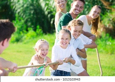 Happy kids with parents playing active games in summer park, tugging war - Powered by Shutterstock