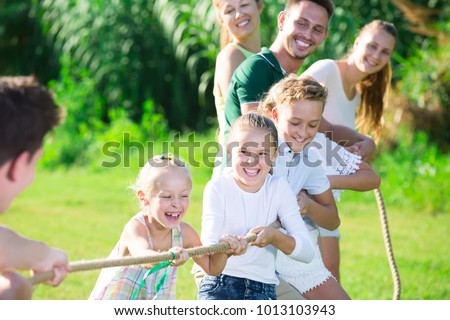 Happy Kids With Parents Playing Active Games In Summer Park Tugging War Happy Kids With Parents Playing Active Games In Summer Park Tugging War