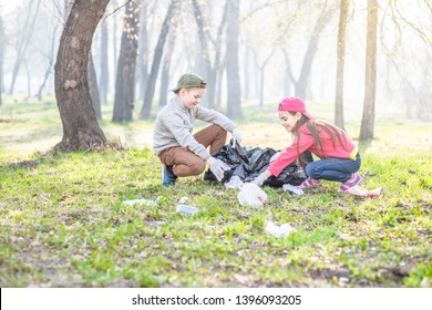 Happy Kids Picking Up Trash In The Spring Park. Empty Space For Text