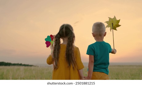 Happy kids play pinwheel in nature. Family. Children friends smiling in park at sunset. Children walk in outdoor. Boy girl holding toy pinwheel in hands. Small kids hold hands. Happy childhood concept - Powered by Shutterstock