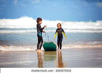 Happy kids play, run and ride on the body board. Children and surfing concept, surfing in a wet suit.