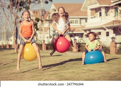 Happy Kids Playing With Inflatable Balls On The Lawn In Front Of House At The Day Time