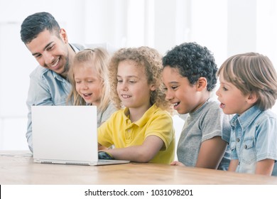 Happy Kids Programming On Laptop During IT Classes With A Spanish Teacher