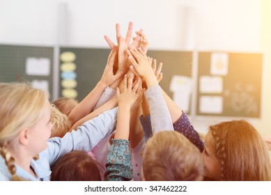 Happy Kids Putting their Hands Together in the Air Inside the Classroom. - Powered by Shutterstock