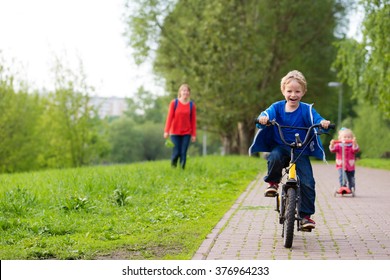 Happy Kids Riding Scooter And Bike In The Park