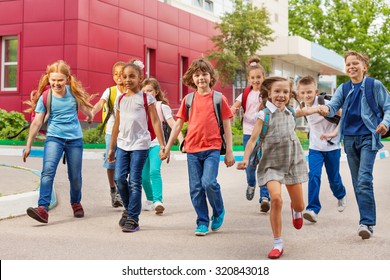 Happy kids with rucksacks walking holding hands